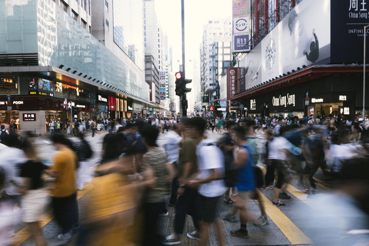 Dynamic scene of people crossing a bustling street in downtown Hong Kong, showcasing urban life.