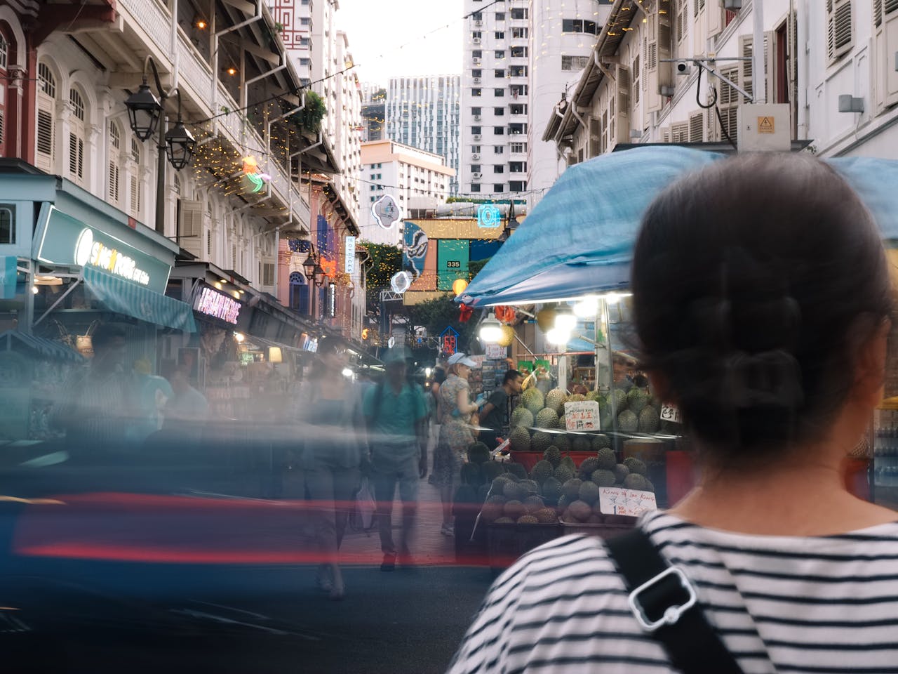 Bustling street scene in Singapore's Chinatown featuring vibrant night market activities and motion blur effects.